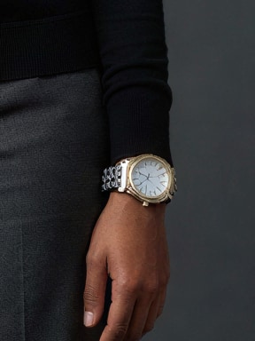 Detailopname: het zilver- en goudkleurige horloge om de pols van een model