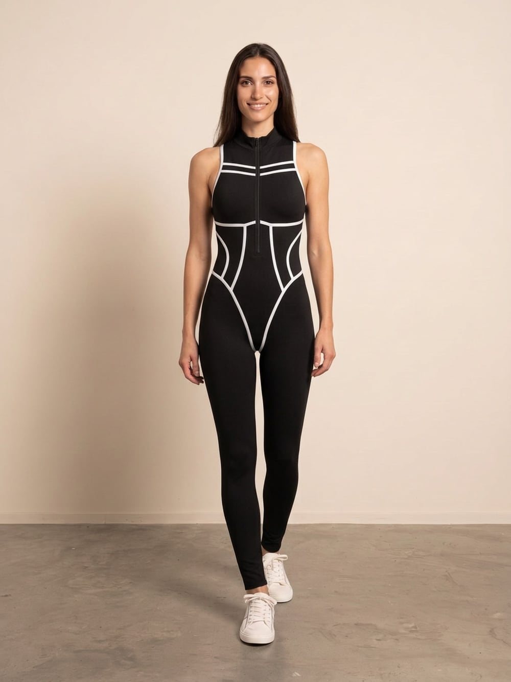 Sara draagt een zwarte mouwloze corset jumpsuit met witte biezen en rits, recht van voren, glimlachend
