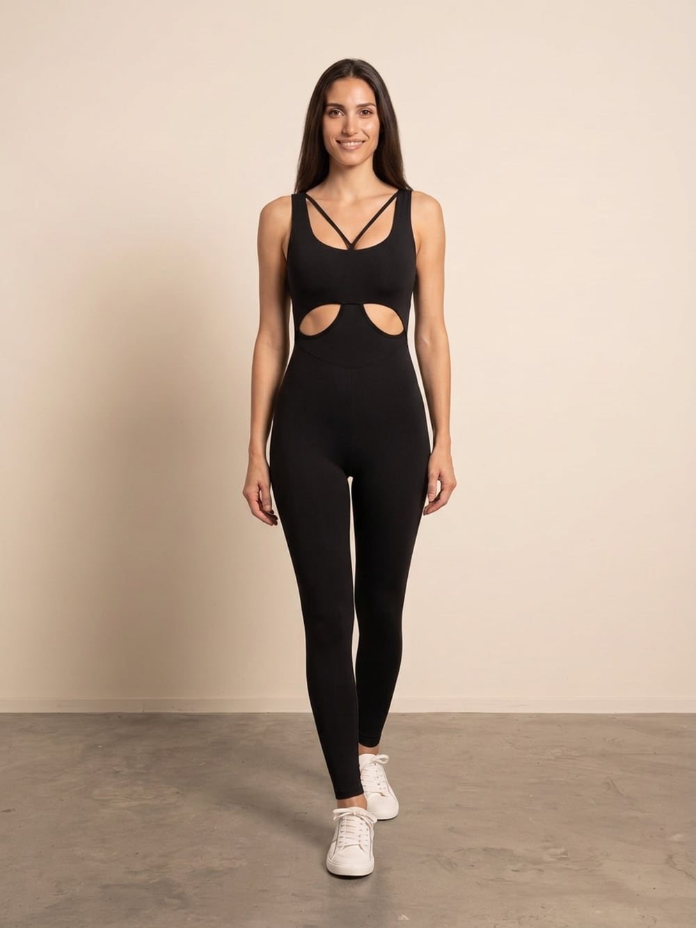 Sara draagt een zwarte jumpsuit met dunne bandjes en open taille, recht van voren, glimlachend
