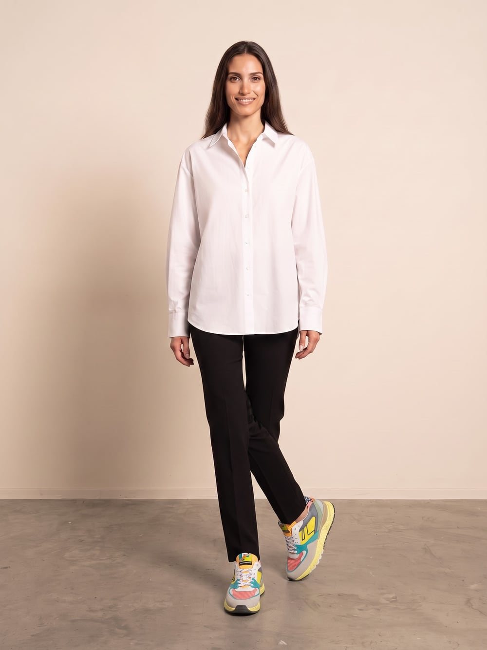 Sara draagt sneakers in grijs, geel, turquoise en koraalrood met gespikkelde gele zool, recht van voren, glimlachend