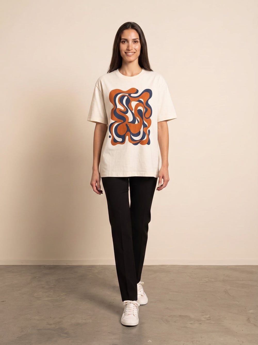 Sara draagt een ecru T-shirt met een abstracte print in oranje en donkerblauw, recht van voren, glimlachend